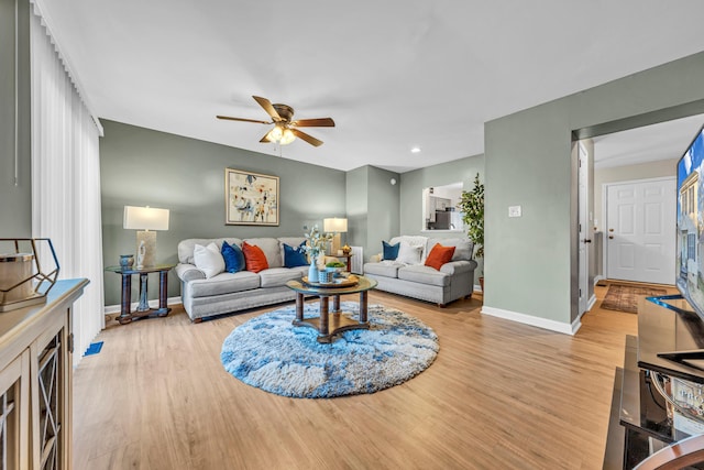 living room with light hardwood / wood-style floors and ceiling fan