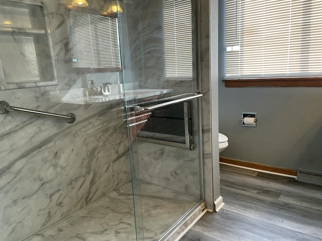 bathroom featuring walk in shower, a baseboard heating unit, and hardwood / wood-style floors