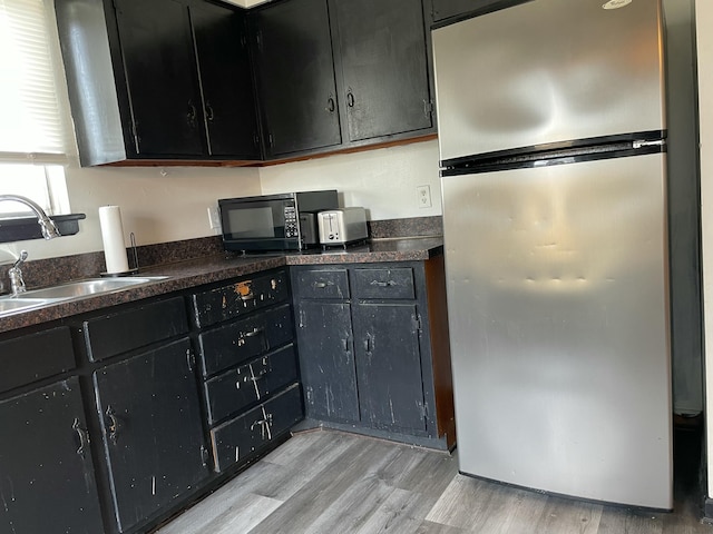 kitchen with stainless steel fridge, sink, and light hardwood / wood-style flooring