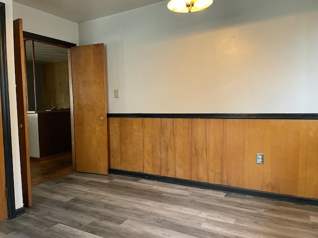 unfurnished room featuring wood-type flooring and wooden walls