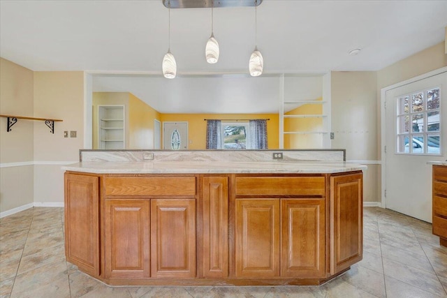 kitchen with a kitchen island, pendant lighting, plenty of natural light, and light stone counters