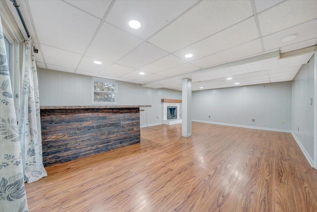 basement with a paneled ceiling and light hardwood / wood-style flooring