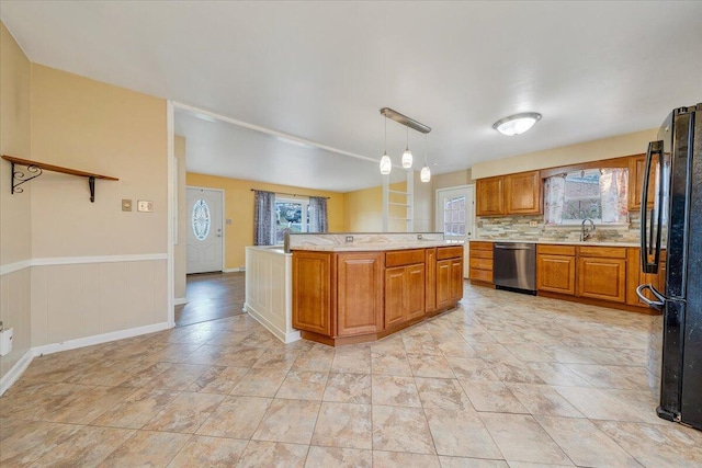 kitchen featuring black refrigerator, decorative light fixtures, dishwasher, a kitchen island, and sink