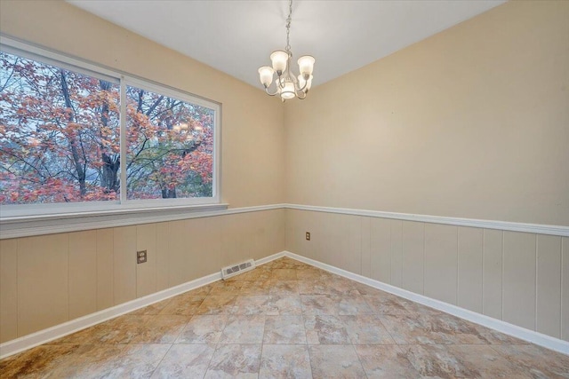 empty room with an inviting chandelier and wood walls