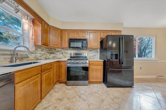 kitchen featuring sink, tasteful backsplash, and black appliances