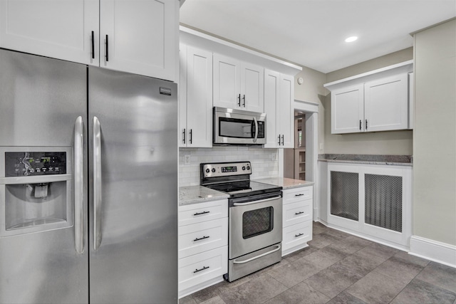 kitchen featuring white cabinetry, appliances with stainless steel finishes, light stone countertops, and tasteful backsplash