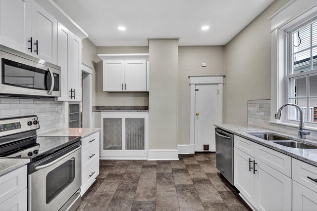 kitchen with sink, stainless steel appliances, light stone counters, tasteful backsplash, and white cabinets