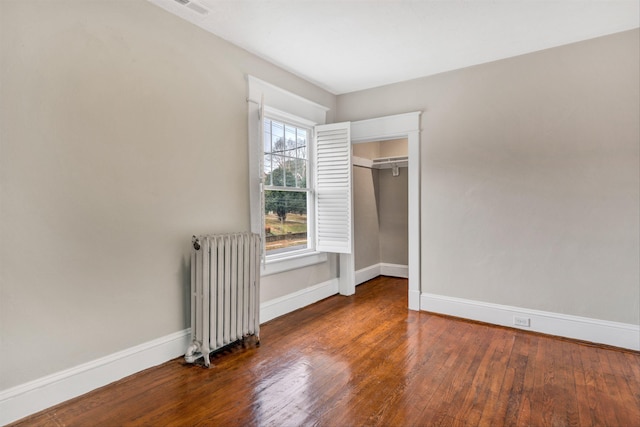 unfurnished bedroom featuring radiator and dark hardwood / wood-style floors