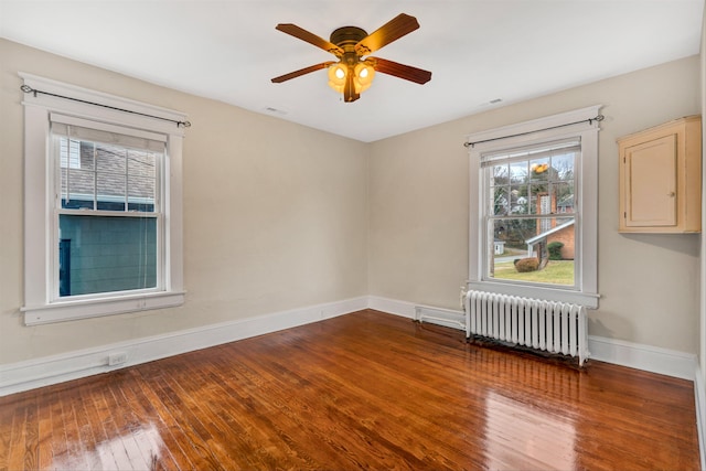 spare room with ceiling fan, radiator, and hardwood / wood-style floors