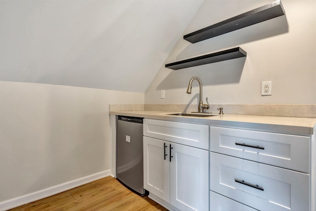 kitchen featuring lofted ceiling, sink, white cabinetry, light hardwood / wood-style floors, and stainless steel dishwasher