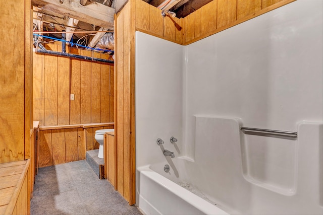 bathroom featuring shower / bath combination, toilet, and wood walls