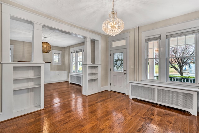 entrance foyer featuring dark wood-type flooring, radiator, and ornate columns