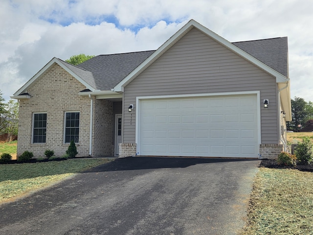 view of front of house featuring driveway, roof with shingles, brick siding, and an attached garage