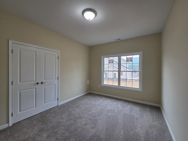 unfurnished bedroom featuring visible vents, carpet, and baseboards