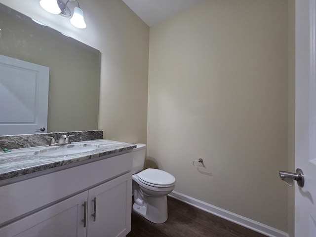bathroom featuring wood finished floors, toilet, vanity, and baseboards