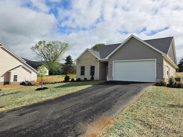 single story home featuring driveway, roof with shingles, a front yard, an attached garage, and brick siding