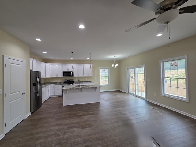 kitchen featuring light stone countertops, a sink, appliances with stainless steel finishes, and dark wood-style flooring