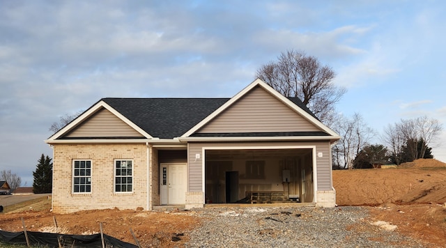 view of front facade featuring a garage, driveway, roof with shingles, and brick siding