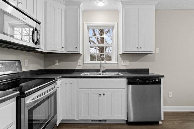 kitchen with a textured ceiling, stainless steel appliances, white cabinetry, and sink