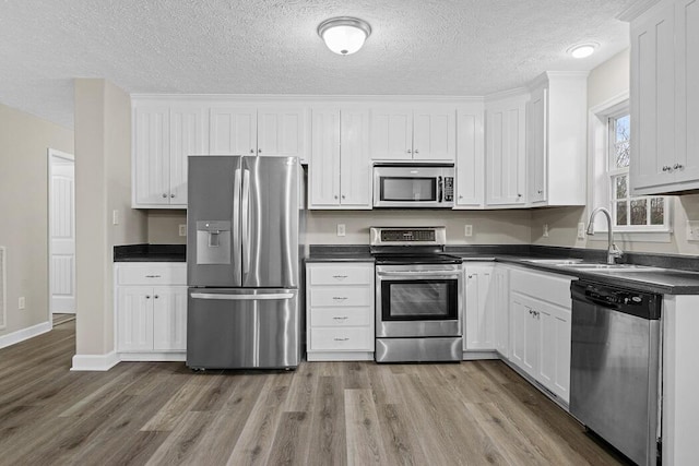 kitchen with white cabinets, sink, stainless steel appliances, and light hardwood / wood-style floors