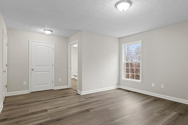 unfurnished room featuring a textured ceiling and dark hardwood / wood-style floors