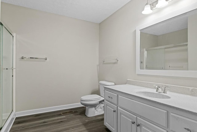 bathroom with a shower with shower door, a textured ceiling, toilet, and vanity