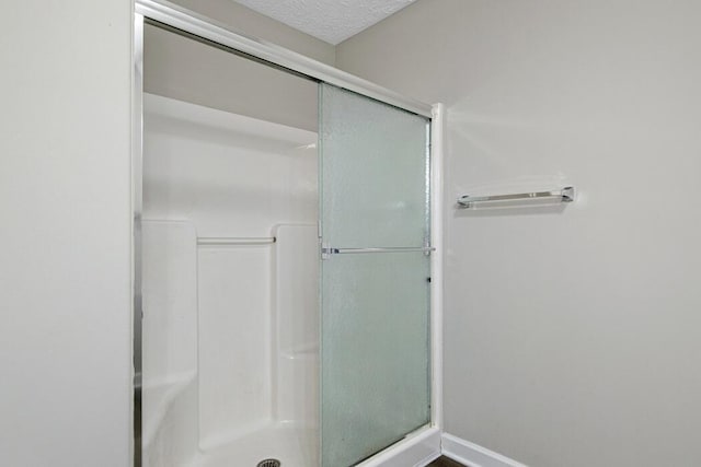 bathroom with a shower with shower door and a textured ceiling