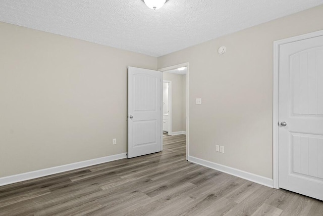 empty room with a textured ceiling and light hardwood / wood-style floors