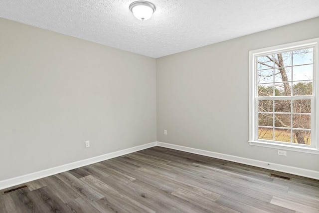 spare room featuring hardwood / wood-style flooring and a textured ceiling