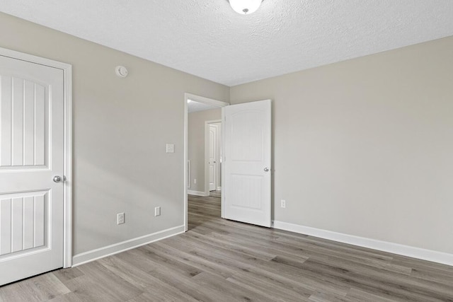 empty room with a textured ceiling and light hardwood / wood-style floors