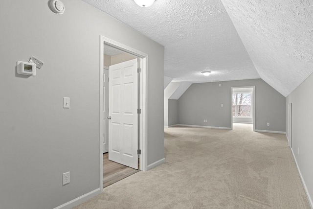 bonus room with lofted ceiling, light colored carpet, and a textured ceiling