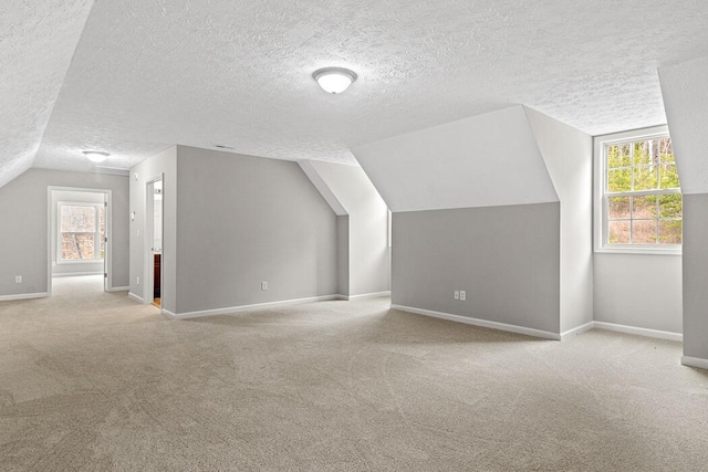 bonus room featuring vaulted ceiling, a textured ceiling, and light carpet