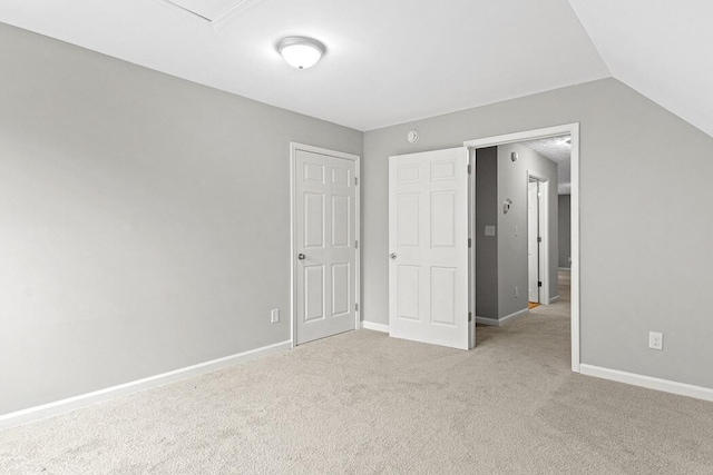 unfurnished bedroom featuring light carpet and lofted ceiling