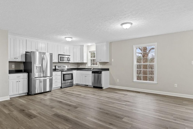 kitchen with sink, white cabinetry, light hardwood / wood-style flooring, and stainless steel appliances