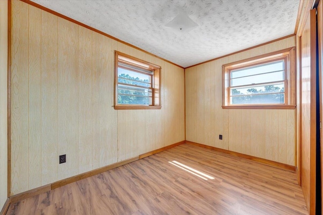 empty room with a wealth of natural light, light hardwood / wood-style flooring, crown molding, and a textured ceiling