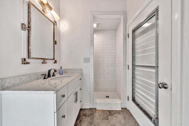 bathroom with a tile shower and vanity