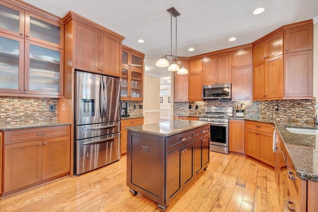 kitchen with a kitchen island, a sink, light wood-style floors, appliances with stainless steel finishes, and brown cabinets