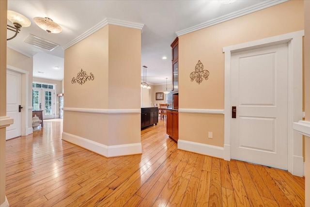 corridor with baseboards, visible vents, crown molding, and light wood finished floors