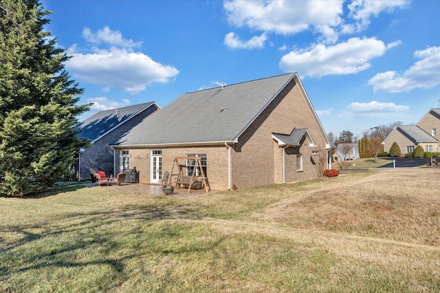 back of house with brick siding, a patio, and a lawn