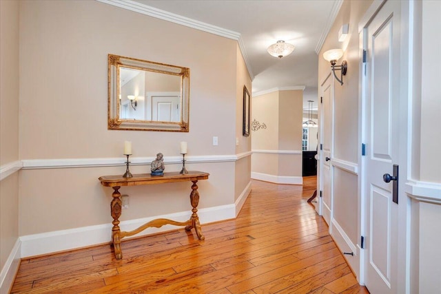 hall with baseboards, light wood finished floors, and crown molding