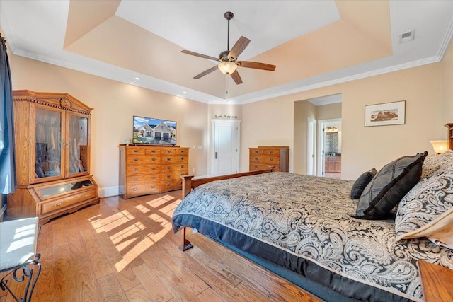 bedroom featuring light wood-type flooring, visible vents, and a raised ceiling