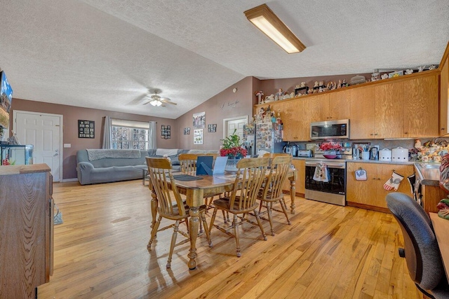 dining area featuring light wood-type flooring, ceiling fan, lofted ceiling, and a textured ceiling