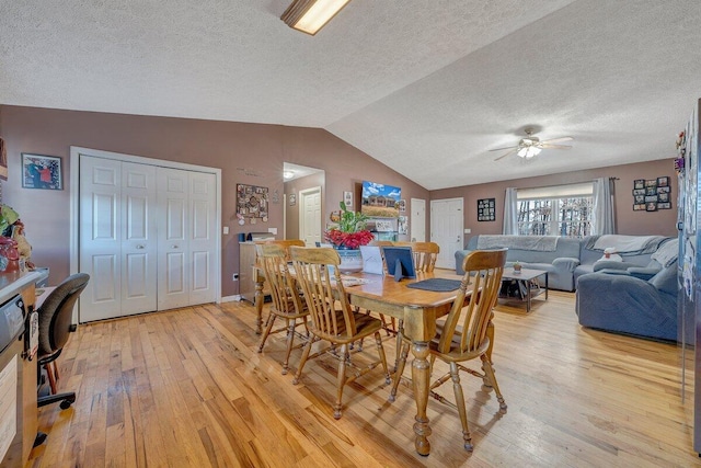 dining space with vaulted ceiling, ceiling fan, a textured ceiling, and light hardwood / wood-style floors