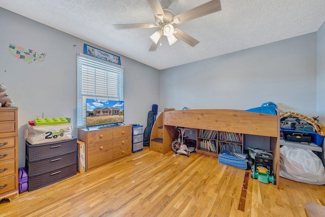 bedroom featuring ceiling fan, a textured ceiling, and light hardwood / wood-style floors