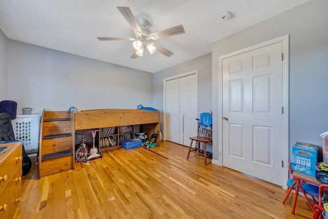 bedroom with ceiling fan, a closet, a textured ceiling, and light hardwood / wood-style floors