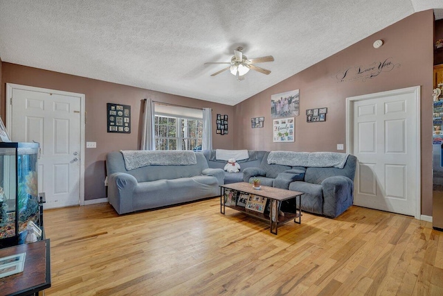 living room featuring ceiling fan, a textured ceiling, light hardwood / wood-style flooring, and lofted ceiling