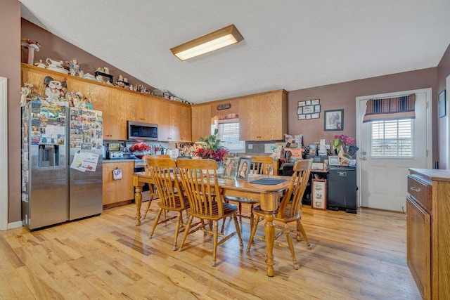 dining space featuring lofted ceiling and light hardwood / wood-style floors