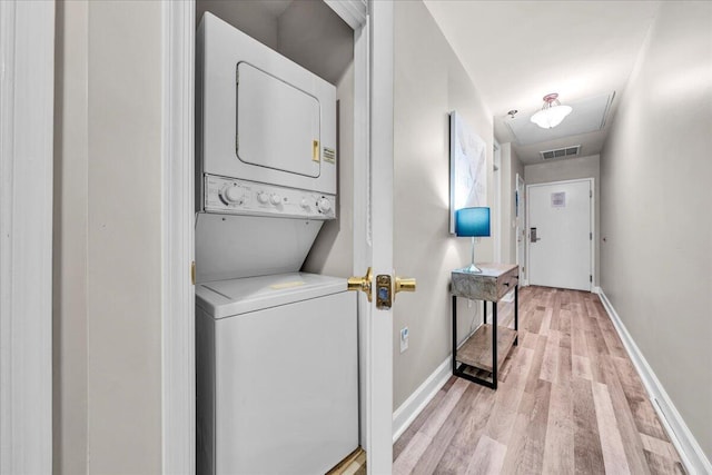 laundry room featuring stacked washer / drying machine and light hardwood / wood-style floors