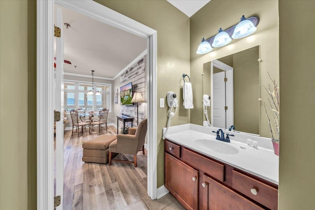 bathroom featuring crown molding, wood-type flooring, and vanity