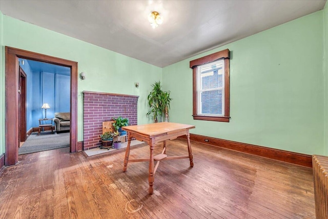 home office featuring radiator heating unit, hardwood / wood-style floors, and a fireplace